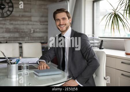 Portrait souriant homme d'affaires confiant assis à table dans un bureau moderne Banque D'Images