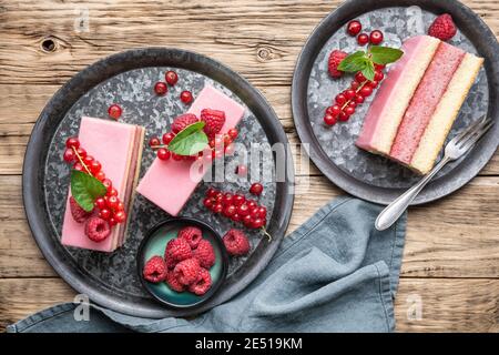 Délicieux et rafraîchissant dessert juteux, gâteau au punch recouvert de glaçage au sucre, framboises fraîches et raisins de Corinthe rouges sur fond de bois Banque D'Images