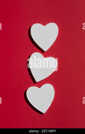 Coeurs blancs sur fond de papier rouge. Concept de la Saint-Valentin Banque D'Images