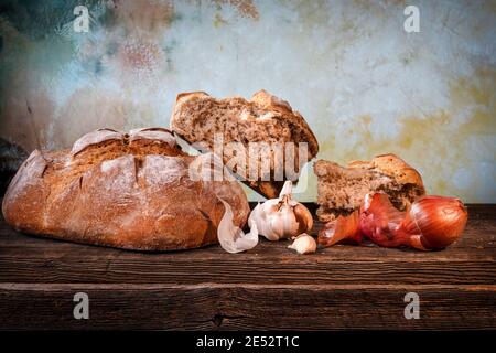 Pain de campagne avec morceaux de miettes, gousses d'ail et échalotes sèches françaises sur un panneau de bois de grange Banque D'Images