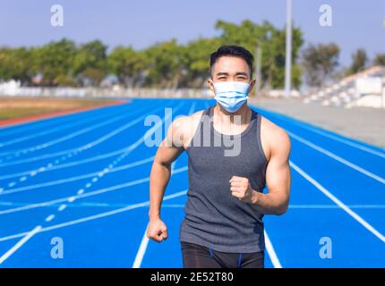 Homme dans un masque médical et courant sur la piste Banque D'Images