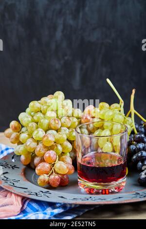 Bouquet de raisins et un verre de jus sur céramique plaque Banque D'Images