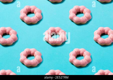 Beignets roses alignés régulièrement sur un fond bleu. Matériau de fond Banque D'Images