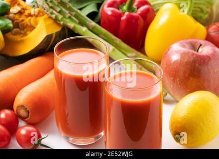 Beaucoup de différents types de légumes et de fruits sur un fond blanc et un verre de jus de légumes Banque D'Images