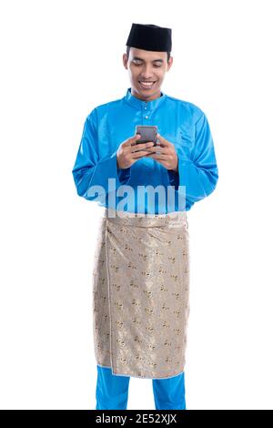 homme musulman asiatique avec téléphone portable portant koko melayu isolé sur blanc Banque D'Images