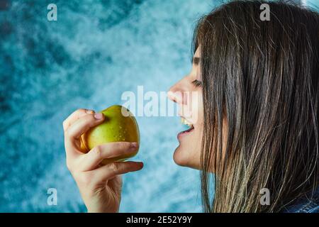 Femme mangeant de la pomme sur fond bleu Banque D'Images