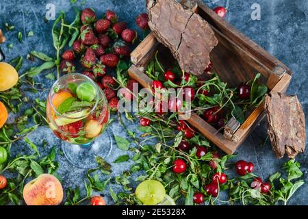 Cerises fraîches rouges sur caisse en bois avec un verre de jus de fruits et fruits frais Banque D'Images