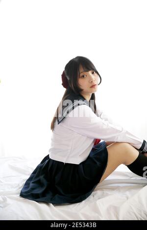 fille d'école japonaise assise sur la chambre dans un ton blanc Banque D'Images