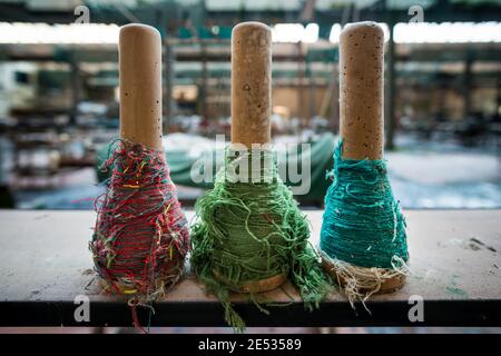 Gros plan de trois bobines colorées de fils couchés une étagère dans une usine de textile abandonnée Banque D'Images