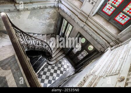 Vue panoramique sur l'escalier en marbre d'un ancien et abandonné maison de campagne de gentry français avec vitraux et un grand piano au sol Banque D'Images