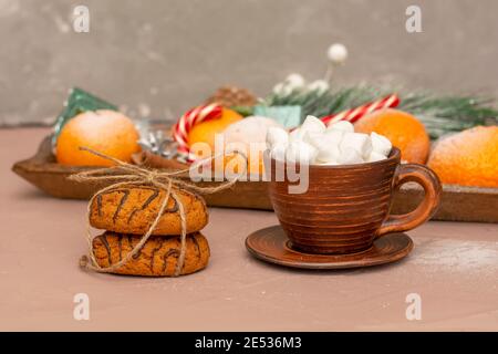 Petit déjeuner romantique en hiver. Café avec guimauves dans une tasse d'argile et biscuits à l'avoine noués par corde. Gros plan, mise au point sélective. Banque D'Images