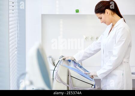 femme médecin boutons-poussoirs sur l'équipement médical, aime travailler à l'hôpital. utiliser des équipements modernes pour le traitement en clinique. médecine et soins de santé co Banque D'Images