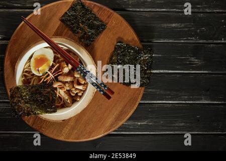 Soupe japonaise de ramen avec poulet, œuf, ail et nouilles sur fond de bois sombre. Nouilles asiatiques miso Ramen Banque D'Images