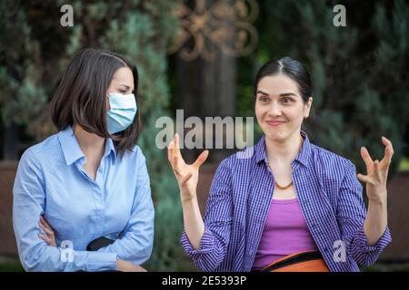 Deux jeunes femmes avec des attitudes différentes à l'égard du coronavirus. Banque D'Images