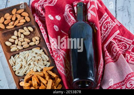 Assortiment d'en-cas et une bouteille de vin sur la table bleue. Craquelins, graines de tournesol, pistaches, amandes Banque D'Images