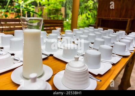 Lait froid dans un pot et une tasse sur l'ancien table en bois à l'extérieur Banque D'Images