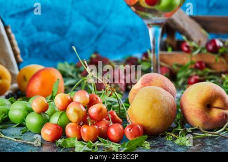 Pêches fraîches, cerises, tranches de citron et menthe sur fond de marbre Banque D'Images