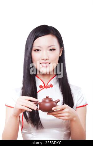Portant cheongsam jeune femme orientale tenant une théière de haute qualité photo Banque D'Images