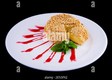 Fromage de brie frite aux graines de sésame, garni de feuilles de menthe fraîche et de sauce aux baies de lingonis. Banque D'Images