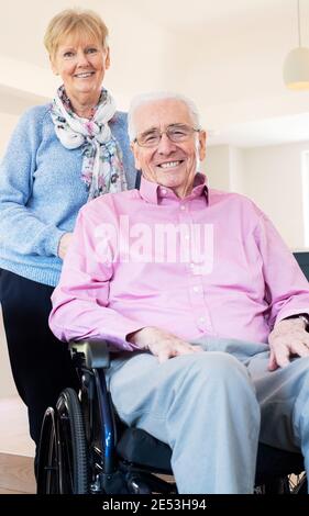 Portrait d'un couple Senior avec mari en fauteuil roulant à la maison Banque D'Images
