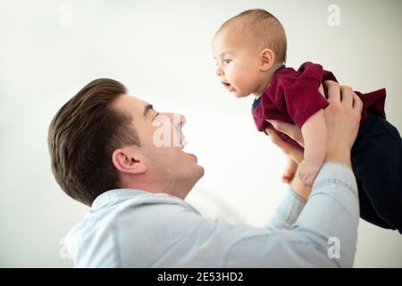 Le père se levait le sourire de bébé fils dans l'air à la maison comme Ils jouent ensemble Banque D'Images