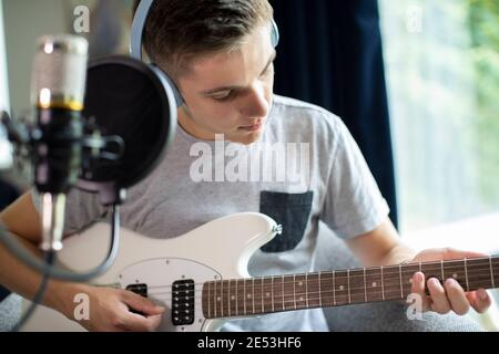 Adolescent qui joue de la guitare et l'enregistrement de la musique à la maison Banque D'Images