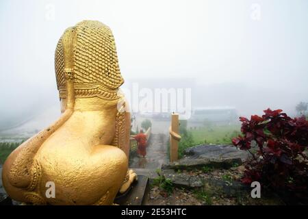 Un moine khmer marchant dans les escaliers devant la statue khmère géante Singha dans la brume. Wat Sampov Pram, Bokor Mountain, Kampot, Cambodge. Banque D'Images