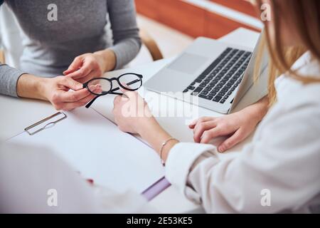 Image focalisée de belles mains de femme donnant du verre pour l'adolescent jeune fille dans la chambre à l'intérieur Banque D'Images