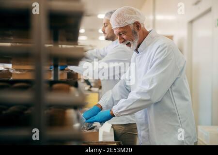 Les travailleurs emballant des biscuits dans des boîtes lorsqu'ils se trouvent dans une usine alimentaire. Banque D'Images