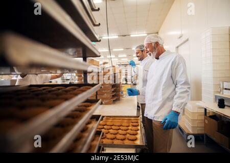 Les travailleurs emballant des biscuits dans des boîtes lorsqu'ils se trouvent dans une usine alimentaire. Banque D'Images