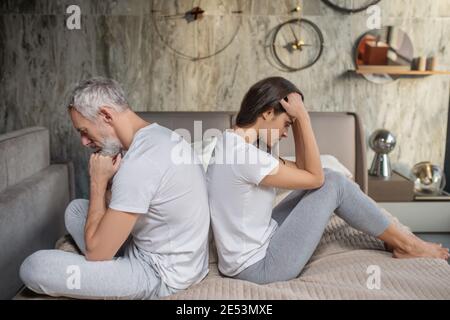 L'homme et la femme détournés assis sur le lit Banque D'Images