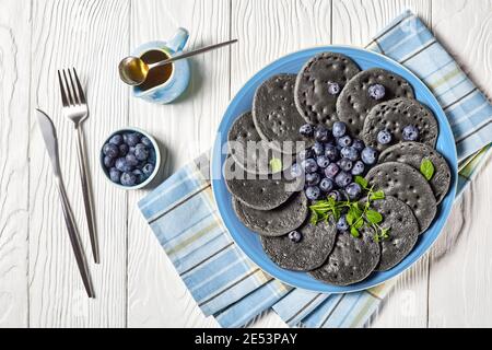 crêpes au charbon actif servies avec des myrtilles et de la menthe sur une assiette sur une table en bois, vue d'en haut, plat Banque D'Images