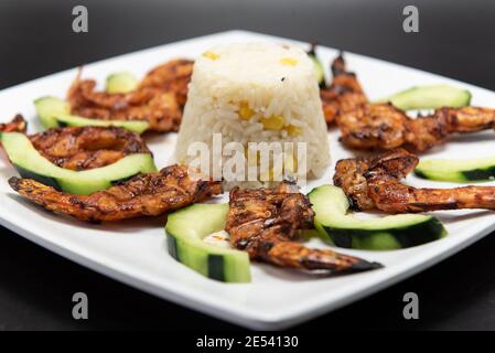 Crevettes zarandeado arrangées dans une présentation parfaite et garnies de tranches concombres sur une assiette Banque D'Images