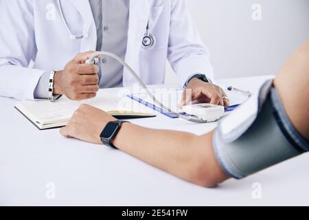 Image en gros plan d'un médecin généraliste mesurant la pression artérielle d'un homme patient Banque D'Images