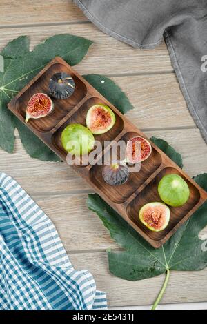 Mûre entière et tranches de figues vertes et noires un plateau en bois avec une feuille et une nappe Banque D'Images