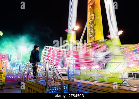 VALENCE, ESPAGNE - 28 décembre 2019 : homme debout devant une attraction du parc des expositions dans un environnement plein de lumières colorées Banque D'Images