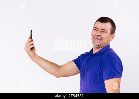 Portrait d'un homme âgé avec une prothèse auditive communiquant par communication vidéo et souriant à la caméra. Arrière-plan blanc. Banque D'Images