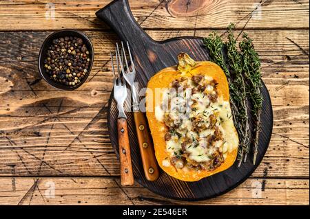 Citrouille cuite farcie de viande hachée, de légumes et d'herbes. fond en bois. Vue de dessus Banque D'Images