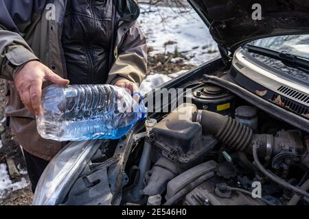 homme versant de l'antigel dans le réservoir de liquide spécial Banque D'Images