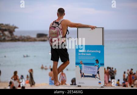 Sydney, Australie. 26 janvier 2021. Un homme se tient à côté d'un panneau d'affichage social à Bondi Beach à Sydney, en Australie, le 26 janvier 2021. Les amoureux de la plage ont été avertis de garder la sécurité dans la mer alors que la vague de chaleur continuait de balayer les États de l'est de l'Australie. Le Bureau de météorologie a également mis en garde de lundi à mercredi sur des conditions de fortes vagues de chaleur dans des zones isolées du Queensland intérieur et du nord de la Nouvelle-Galles du Sud (NSW). Credit: Bai Xuefei/Xinhua/Alay Live News Banque D'Images