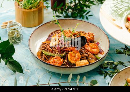 Gros plan sur des nouilles soba de fruits de mer gastronomiques sur du bleu Banque D'Images
