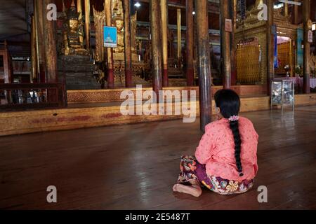 Une femme prie à l'intérieur du monastère de Nga Phe Kyaung, lac Inle, Myanmar. Banque D'Images