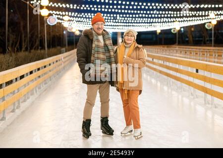 Portrait d'un couple d'âge mûr souriant à l'appareil photo tout en étant debout patinoire ils ont un mode de vie actif Banque D'Images
