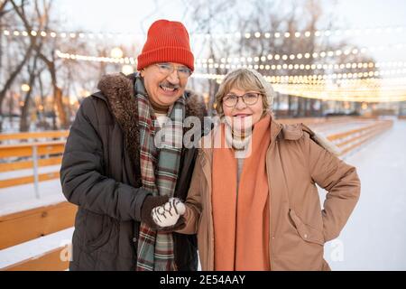 Portrait d'un couple d'âge mûr souriant à l'appareil photo tout en marchant le parc en hiver Banque D'Images