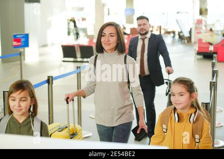 Femme avec ses enfants en vacances, ils se tiennent debout file d'attente et attente de départ à l'aéroport Banque D'Images