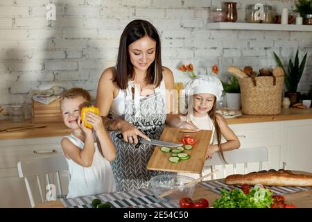 Maman cuisine le déjeuner avec les enfants. Une femme enseigne à sa fille la cuisine de son fils. Végétarisme et alimentation naturelle saine Banque D'Images