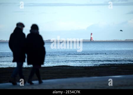 26 janvier 2021, Basse-Saxe, Varel : promenade le long de la plage de Dangast avec vue sur le phare d'Arngast. Photo: Sina Schuldt/dpa Banque D'Images