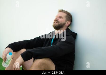 Sportif décontracté et souriant assis à l'extérieur Banque D'Images
