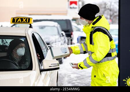 Munich, Allemagne. 26 janvier 2021. Une femme remet une boîte contenant cinquante masques FFP2 à un chauffeur de taxi à un drive-in de masque FFP2 à Munich-Trudering. Au drive-in, les clients peuvent monter directement à un comptoir avec leur voiture et obtenir des masques FFP2. Credit: Matthias balk/dpa/Alay Live News Banque D'Images