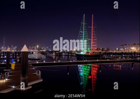 Horizon du port de Dubai creek avec des bateaux et des navires illuminés en couleurs de drapeau pour la journée nationale des émirats arabes unis capturée au Ras al khor, Dubaï Banque D'Images